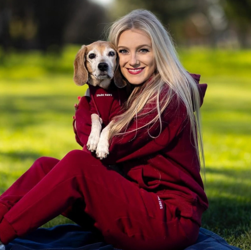a woman with red clothes holding a dog in the park